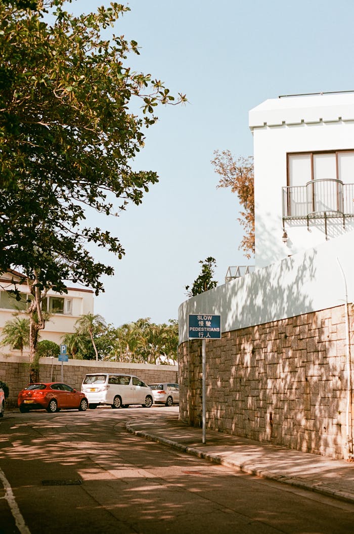 Charming street scene in Hong Kong suburb with trees and parked cars.